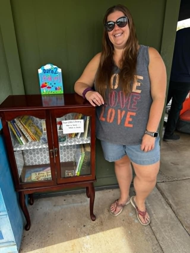 Sara Jean standing by her Little Library